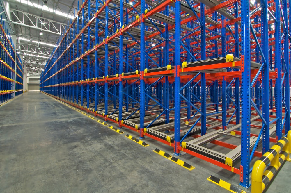 Push-back warehouse racking system with angled racks for efficient LIFO inventory management.