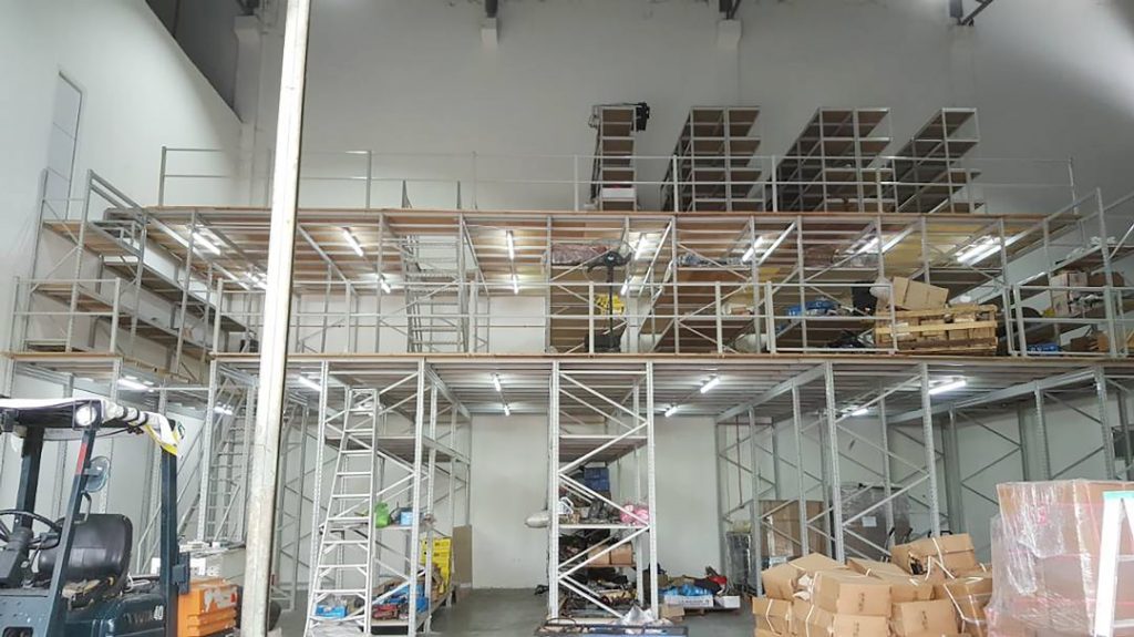 High-capacity racking-supported platform in a warehouse, displaying stacked pallets on lower levels with an elevated work area on top.